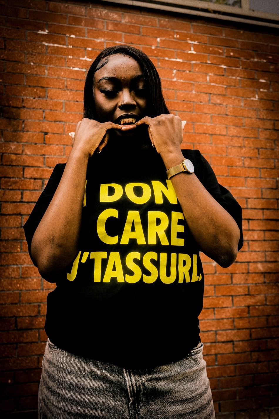 Le tee porté avec le print jaune, devant un mur de brique.